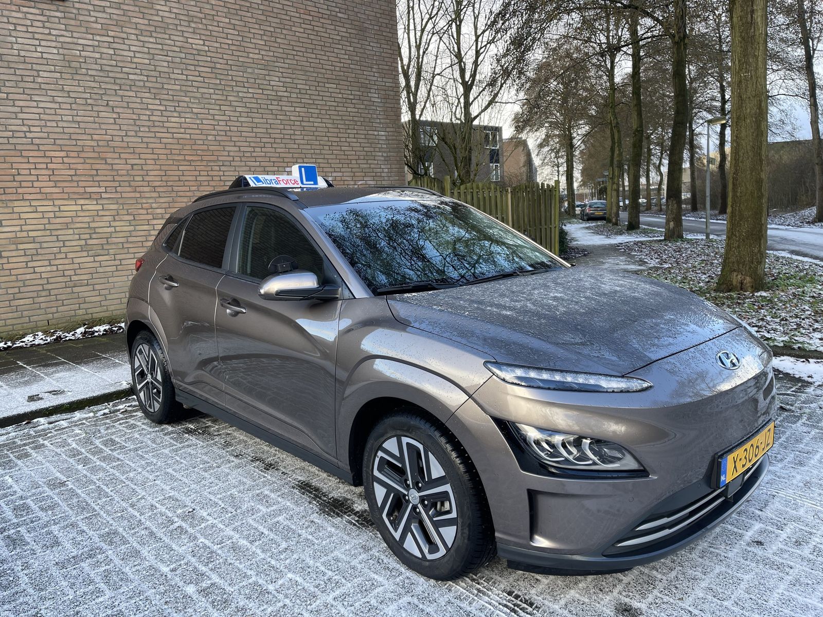De lesauto van LibraForce, een grijze Hyundai Kona met het LibraForce-lesbord op het dak