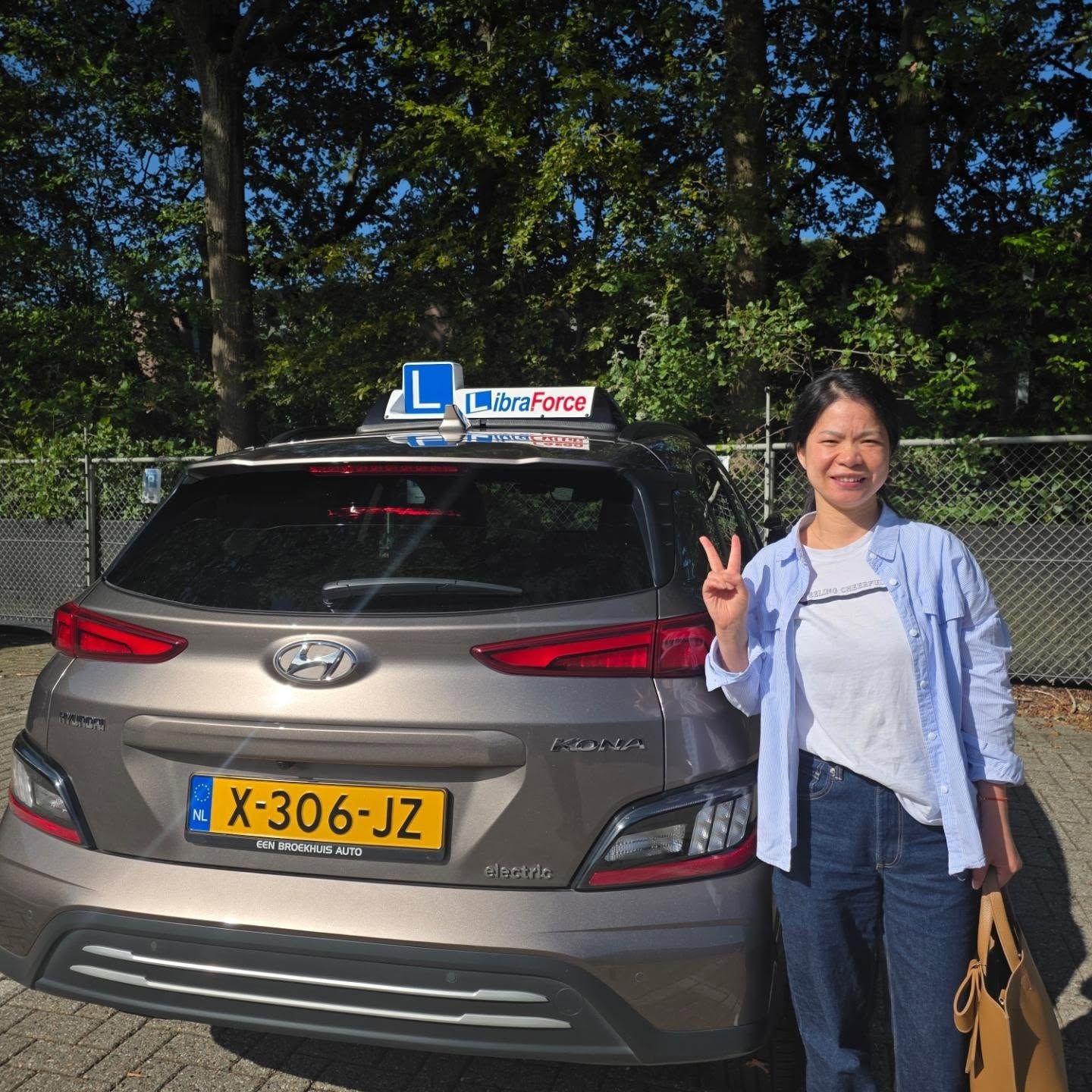 Geslaagde leerling van LibraForce bij de lesauto