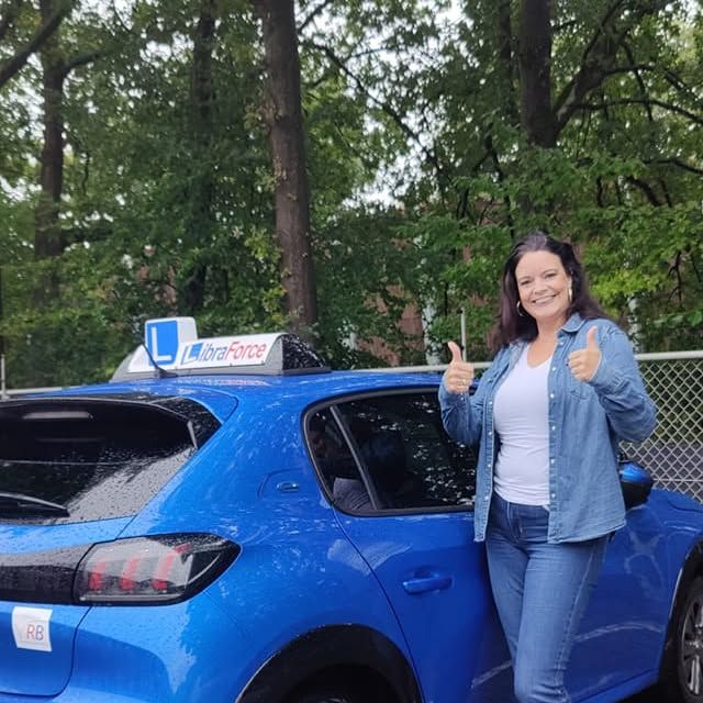 Geslaagde leerling van LibraForce bij de lesauto