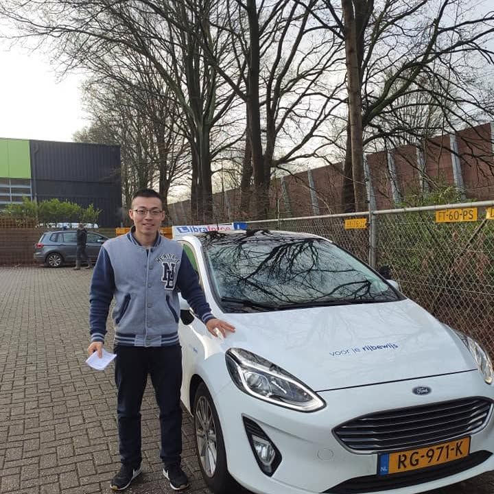Geslaagde leerling van LibraForce bij de lesauto
