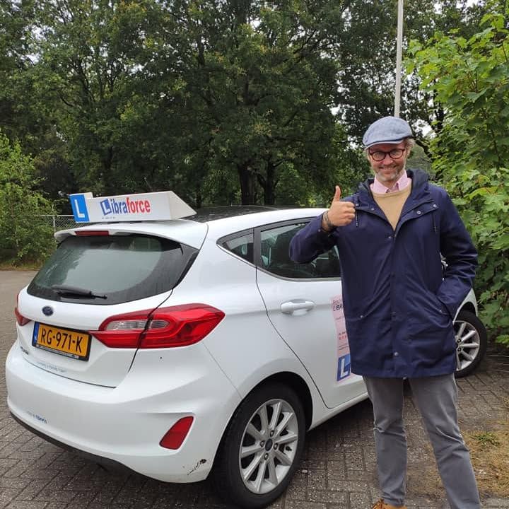 Geslaagde leerling van LibraForce bij de lesauto