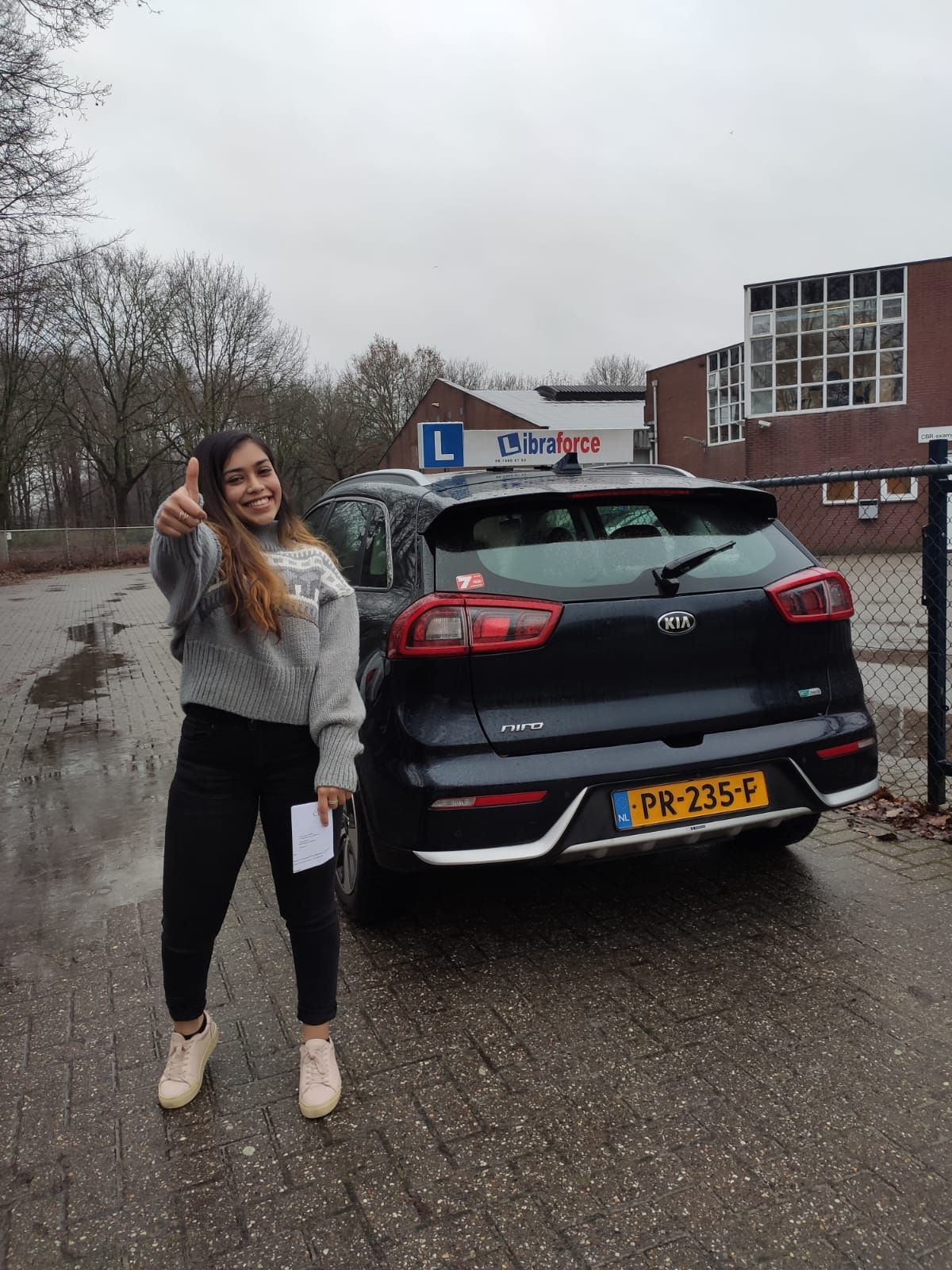 Geslaagde leerling van LibraForce bij de lesauto