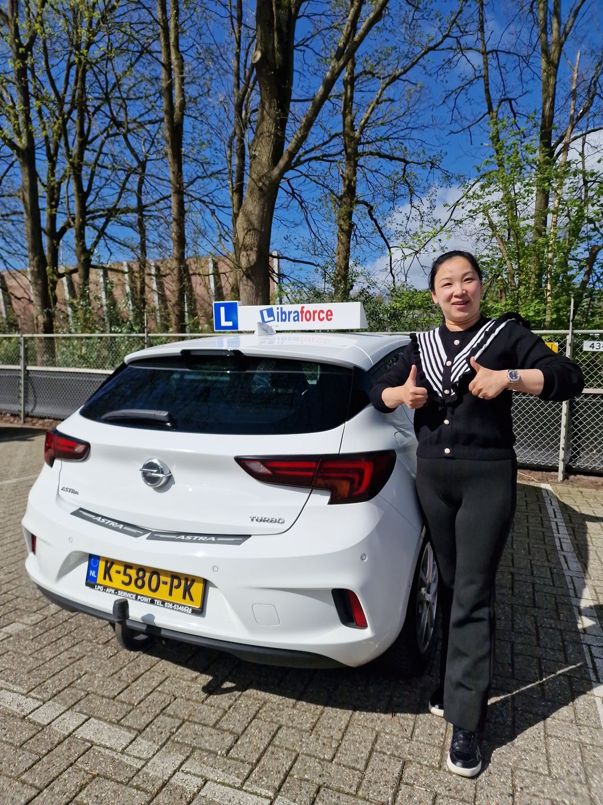 Geslaagde leerling van LibraForce bij de lesauto