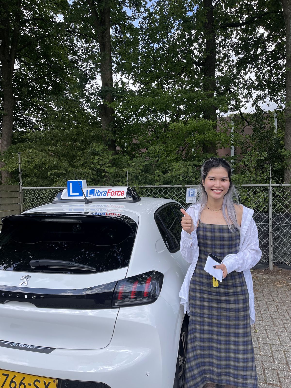 Geslaagde leerling van LibraForce bij de lesauto