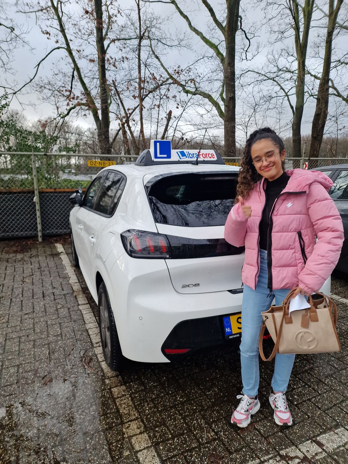 Geslaagde leerling van LibraForce bij de lesauto